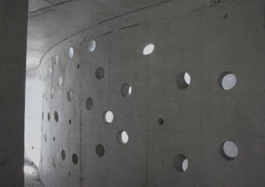 Muro curvo de hormigón con perforaciones circulares